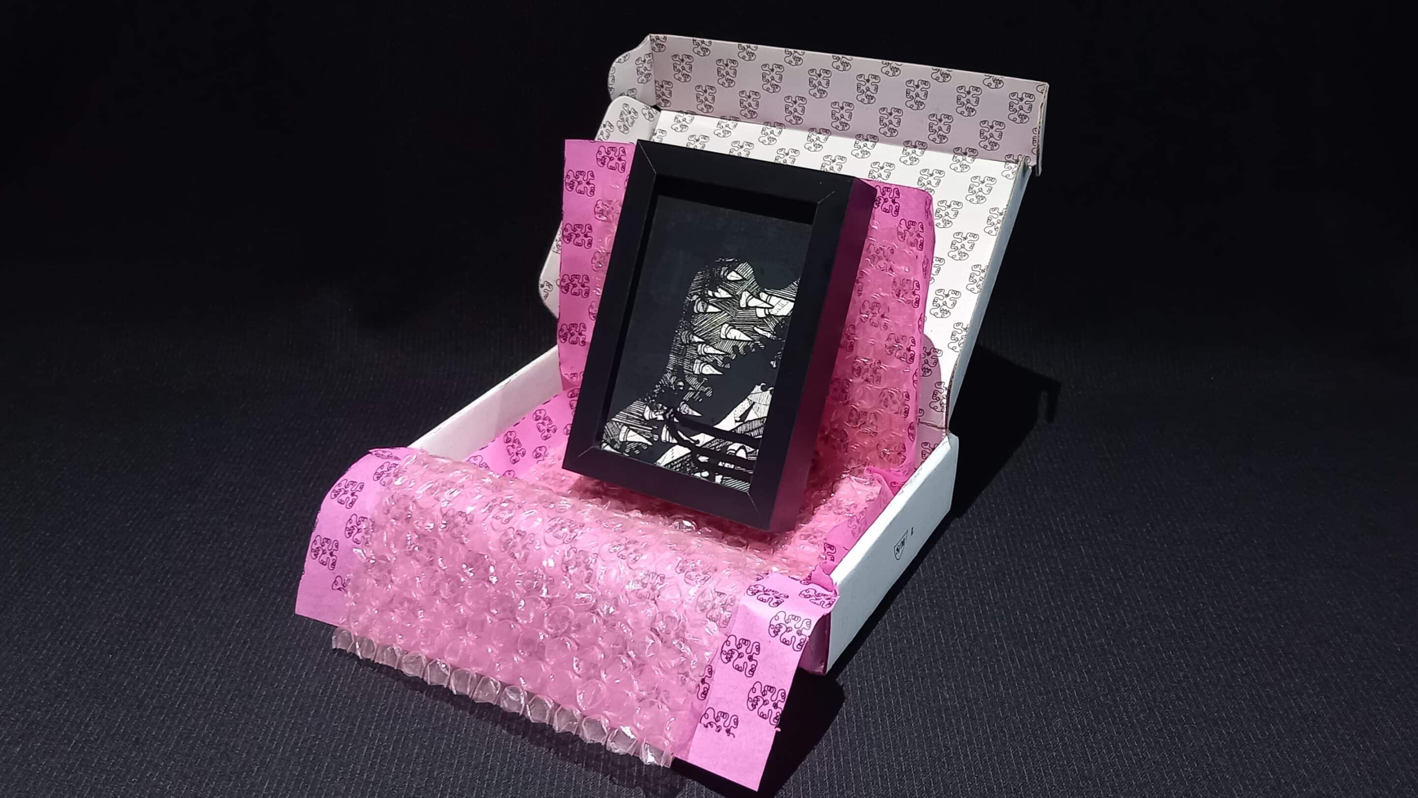 Œuvre encadrée en noir et blanc, sérigraphie unique avec parfois des rehauts de peinture fuchsia. Emballage soigné : papier bulle, papier de soie, et boîte en carton double cannelure décorée à la main en sérigraphie.