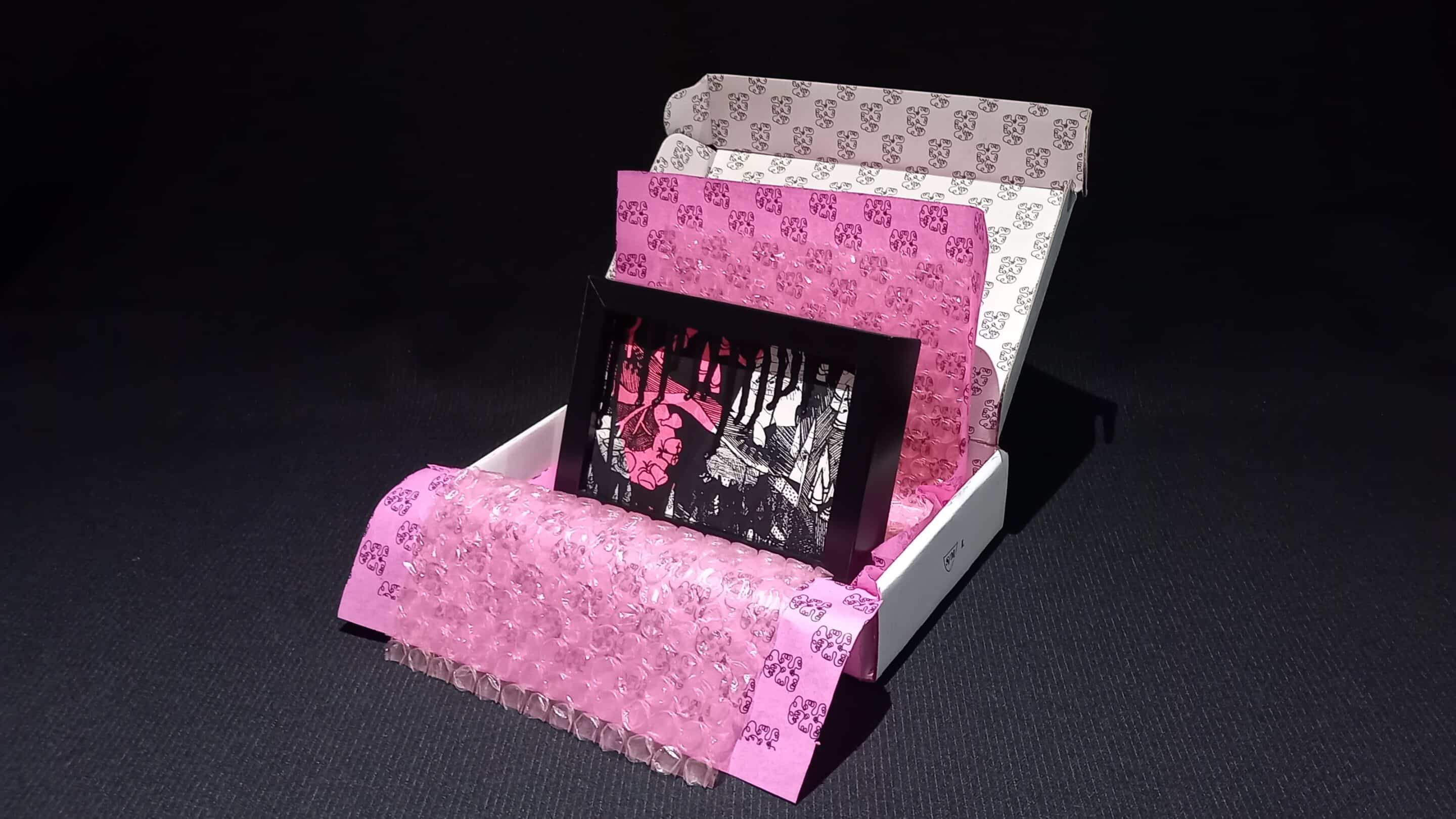 Œuvre encadrée en noir et blanc, sérigraphie unique avec parfois des rehauts de peinture fuchsia. Emballage soigné : papier bulle, papier de soie, et boîte en carton double cannelure décorée à la main en sérigraphie.