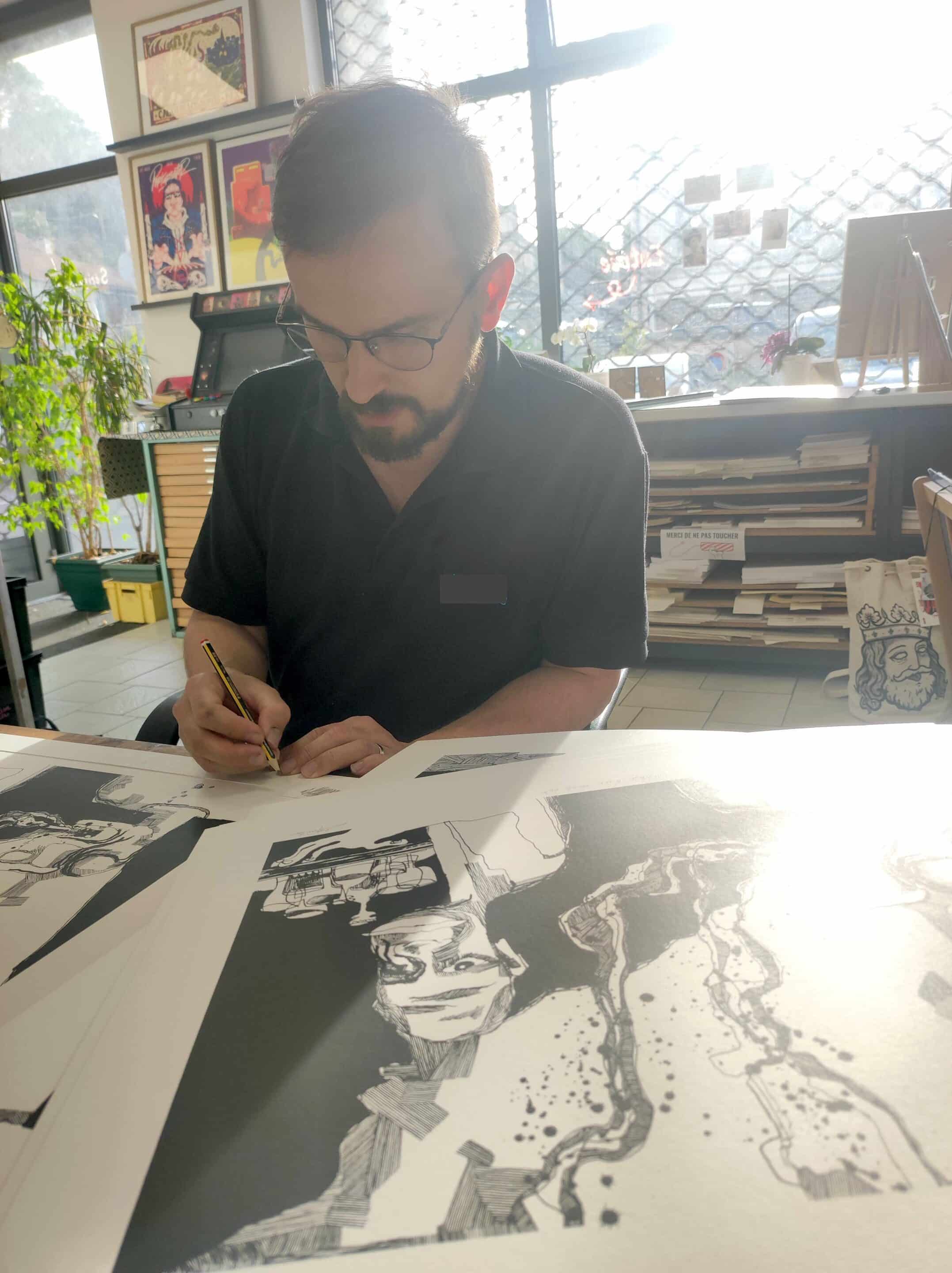 Main signant une sérigraphie en atelier