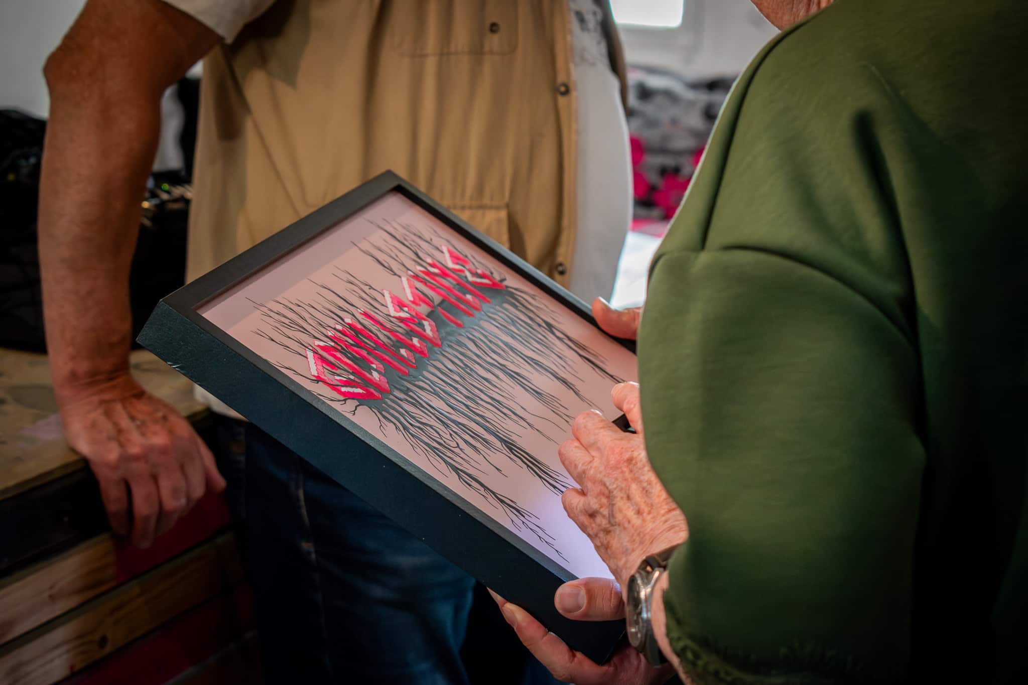 Visiteur tenant la sérigraphie Guillotine de Matthieu Exposito pendant un échange autour de l'œuvre.